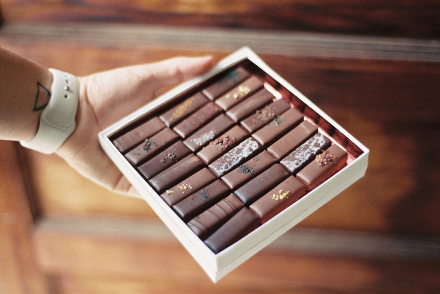 A hand holds a box of artisanal chocolates — chocolates are one of the most reliable products to sell at a fundraiser.