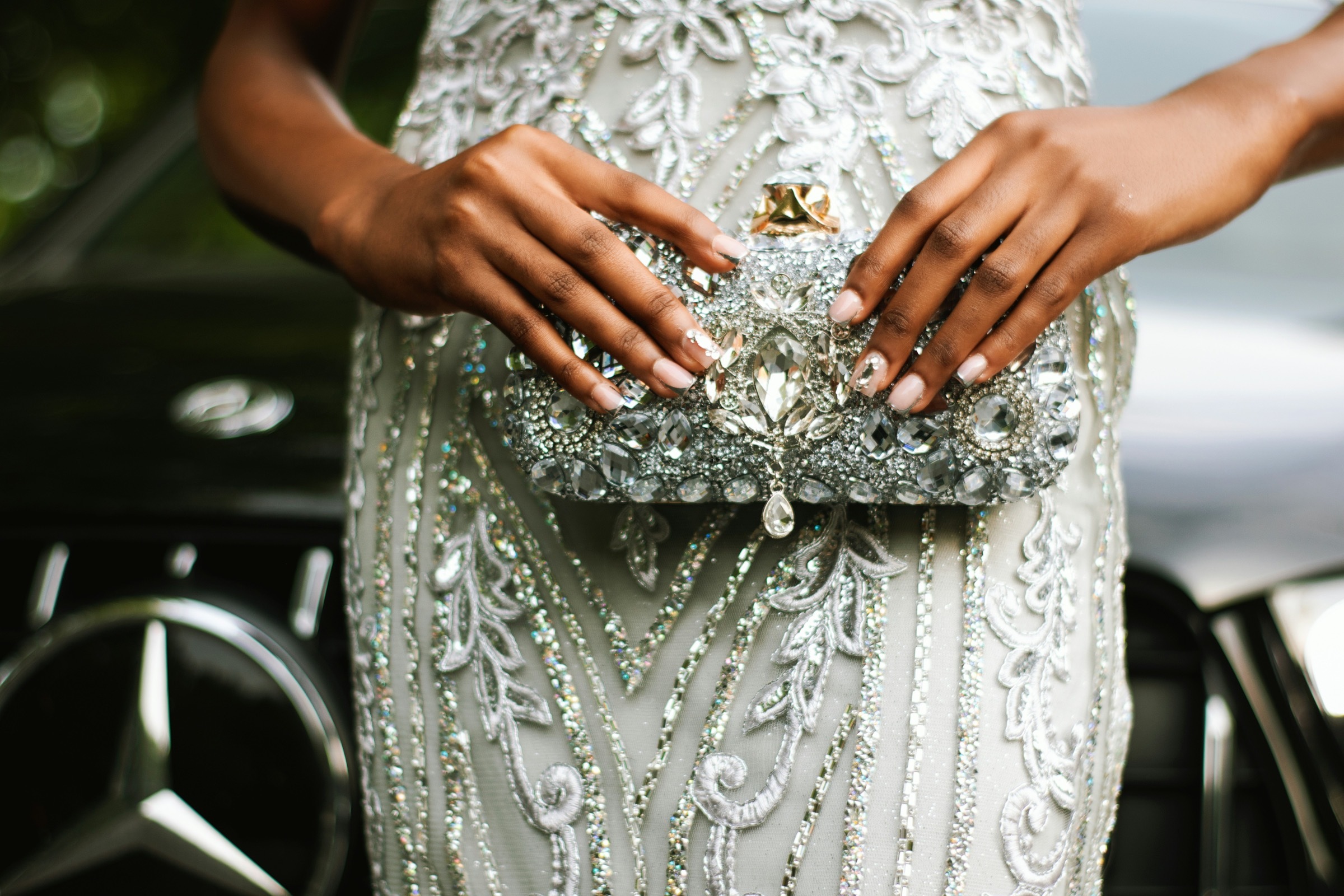 Online prom ticketing guide – hero a close up of a young woman's hands holding a beaded clutch atop her sparkling prom dress.